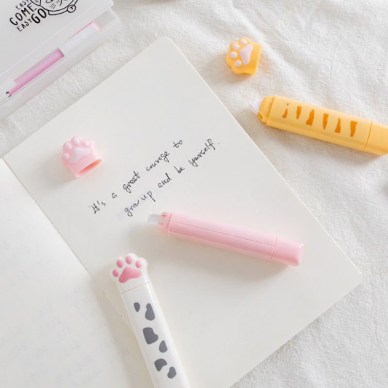 Cat paw correction tape dispensers placed on an open notebook