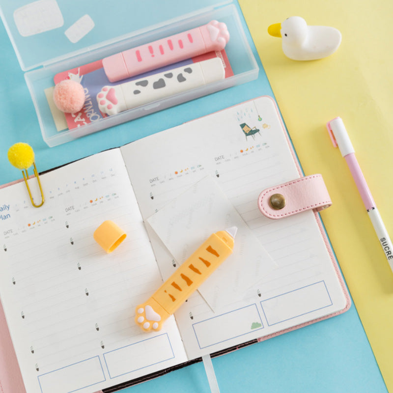 Pink correction tape dispensers placed on an open notebook
