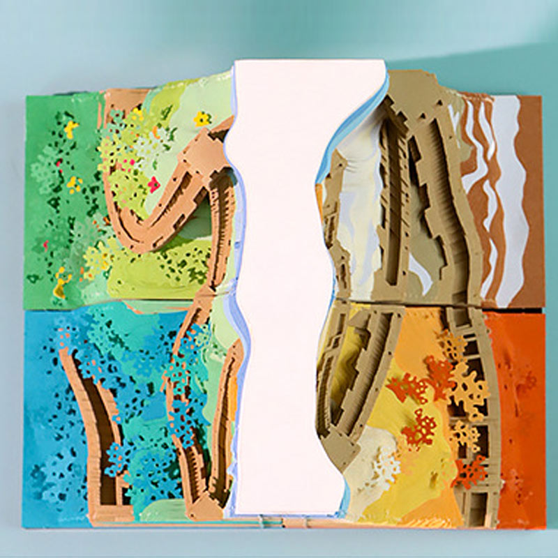 Layered paper landscape showing four seasonal scenes with colorful details