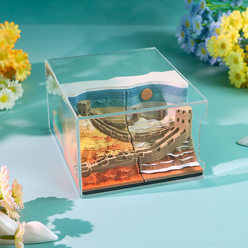 Four-season paper landscape sculpture displayed inside a clear protective case