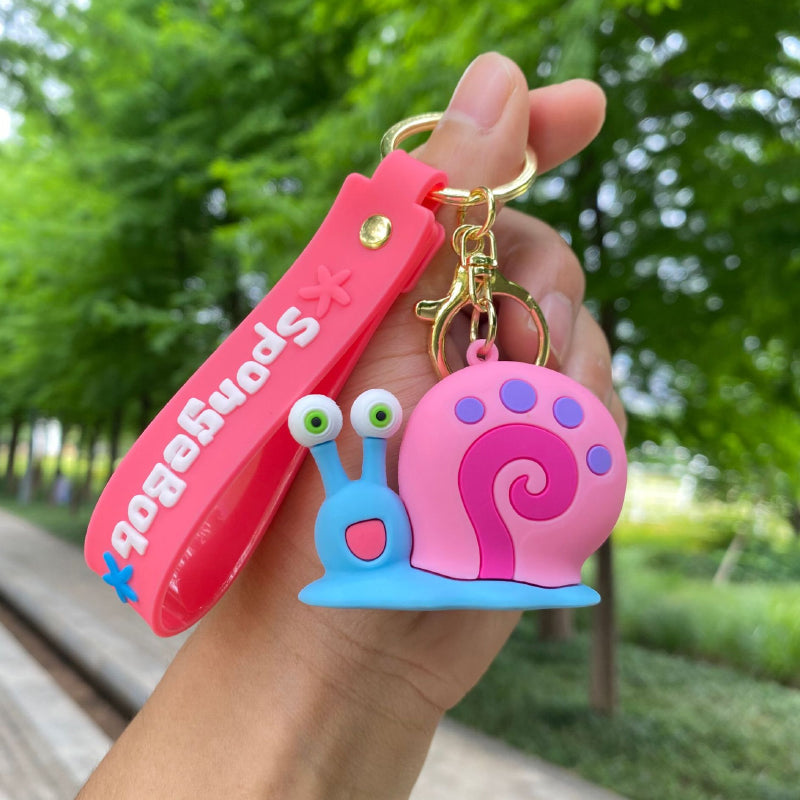 Pink snail keychain with blue body, raised eyes and decorative wrist strap