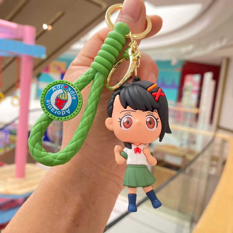 School-style doll keychain with green braided strap and metal ring