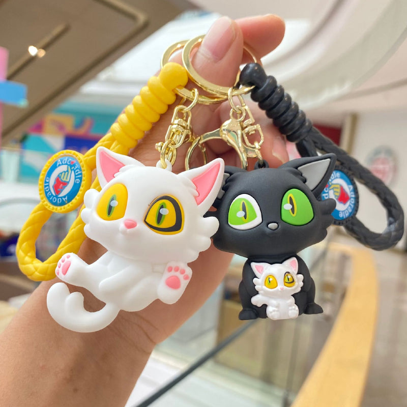 White and black cat keychain pair with braided straps and metal rings